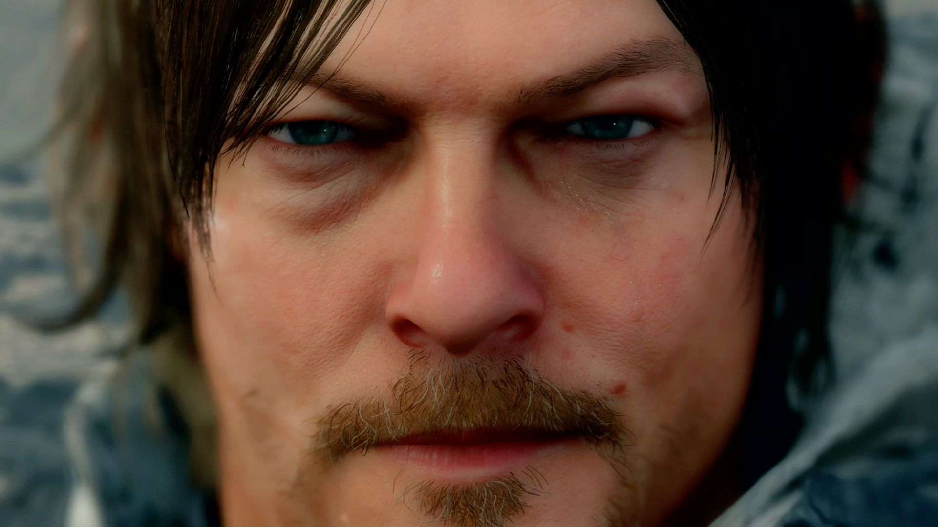 Screenshot di Norman Reedus/Sam Porter Bridges da Death Stranding mentre cammina nel paesaggio post-apocalittico con i pacchi sulle spalle
